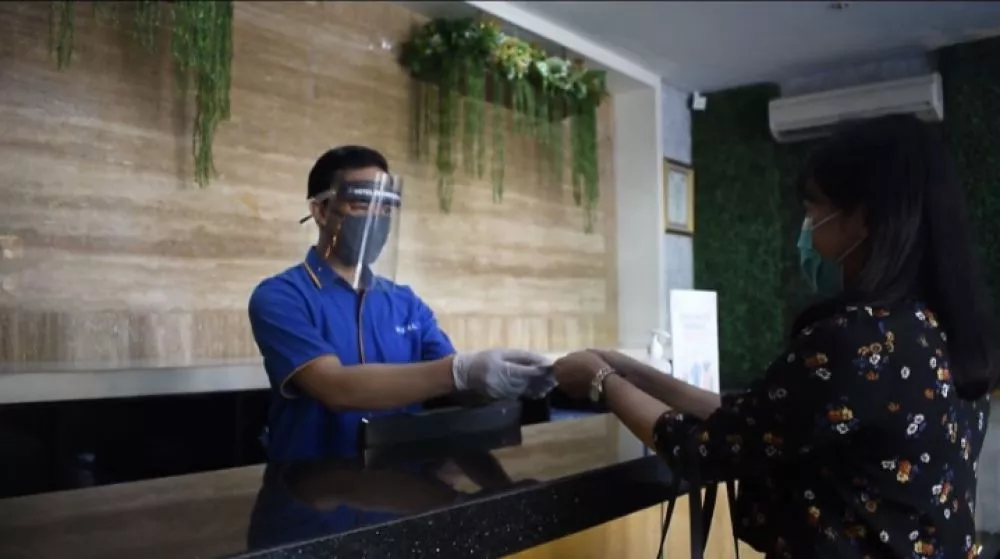Petugas mengenakan alat pengamanan kesehatan saat melayani tamu