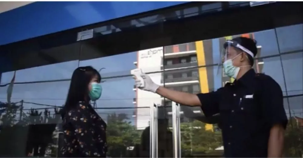 Petugas memeriksa suhu tubuh tamu yang akan memasuki hotel