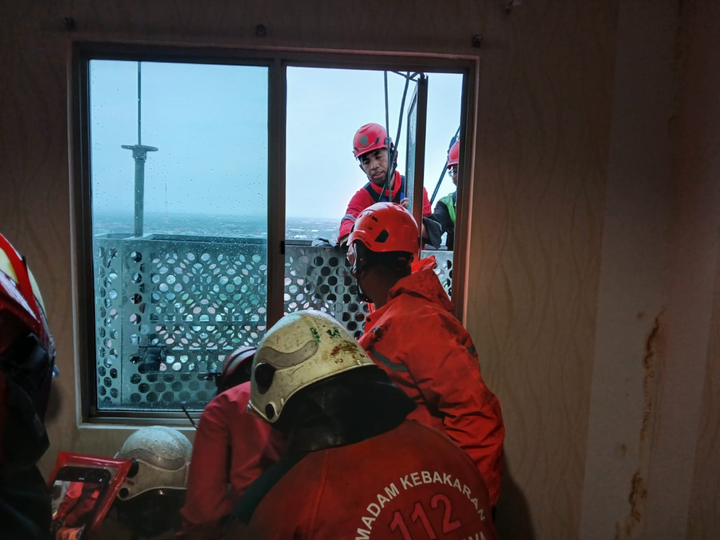 Tim DPKP Surabaya saat melakukan evakuasi pekerja yang terjebak di gondola apartemen Waterplace Surabaya. (Dok. Kedaruratan 112 Surabaya).